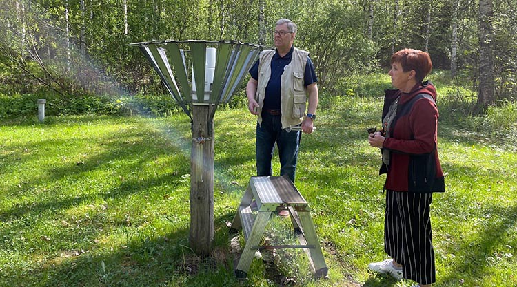 Observatören och representanten för Meteorologiska institutet tittar på regnmätaren på gräsområdet.