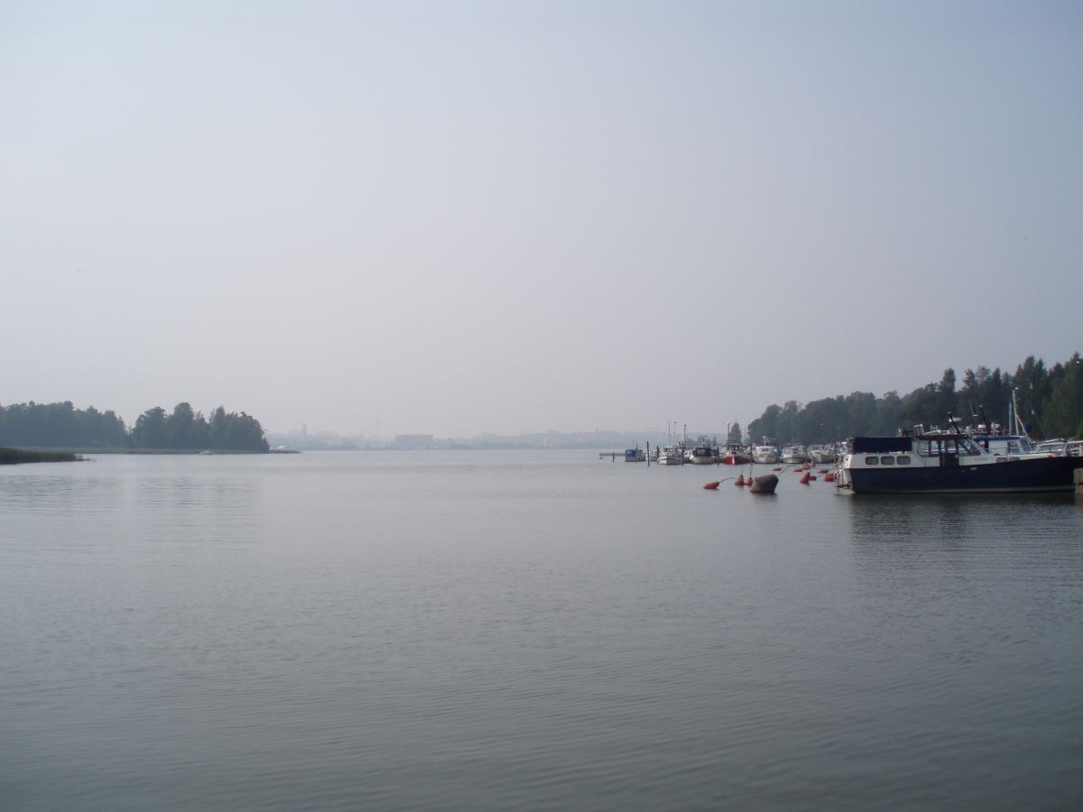 Solrök över havet vid båthamn. Man kan inte se långt bort.