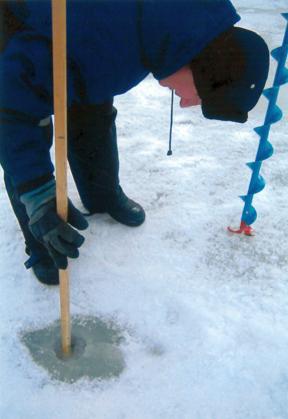 Mannen har borrat en hål och håller en mätsticka i det.