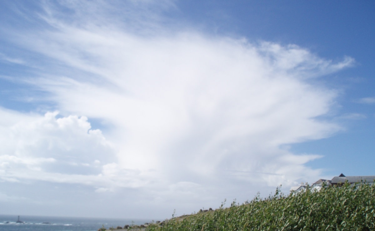 På den blå himlen finns ett högt moln med en mörk och regnig nedre del och en ljus övre del.