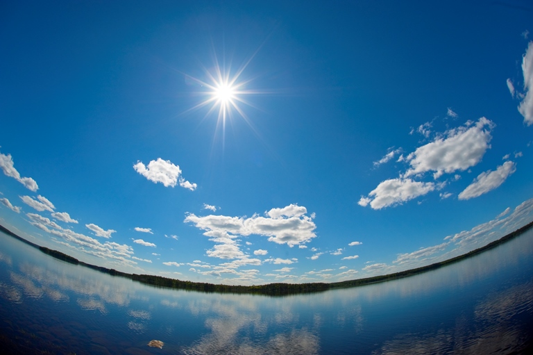 Solen skiner, bara några små cumulu-moln över sjö.