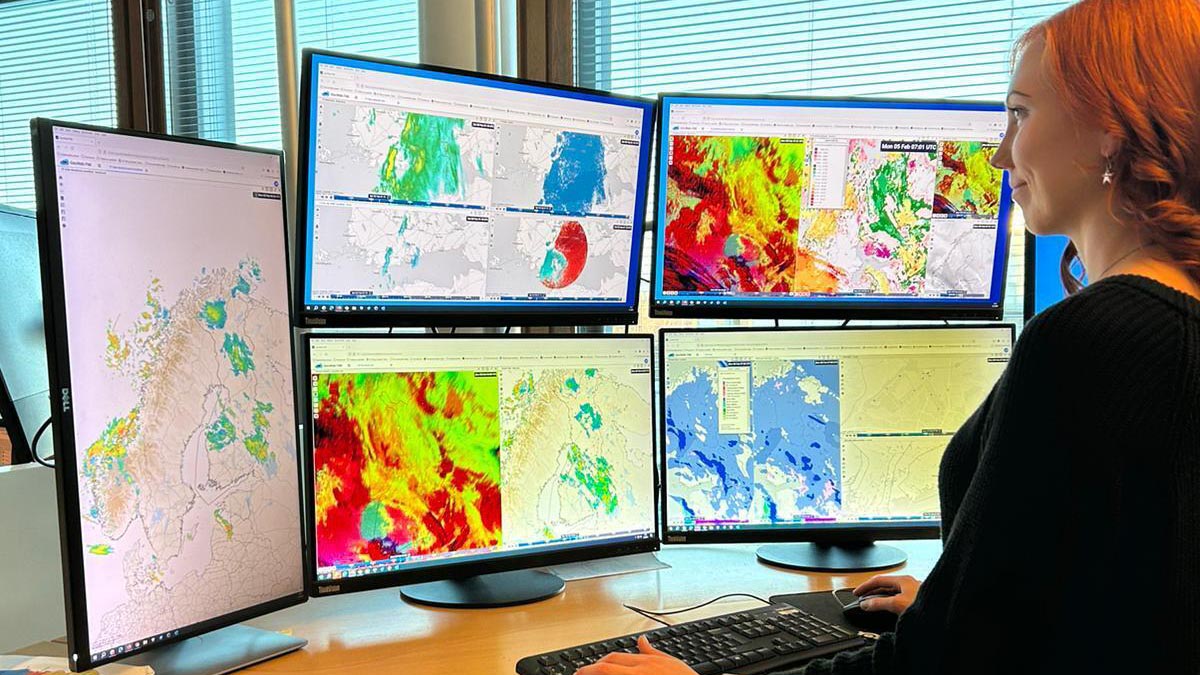 Jourhavande meteorolog på arbetsplatsen framför flera skärmar som visar olika väderdata.