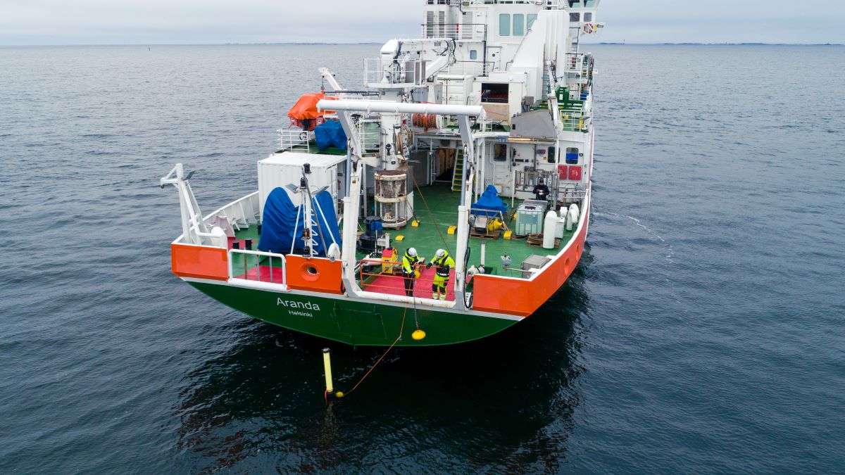 Två man är ombord på Aranda och lyfter en boj från havet med en rep.