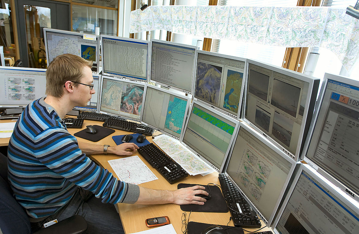 Meteorologen omges av flera datorskärmar.